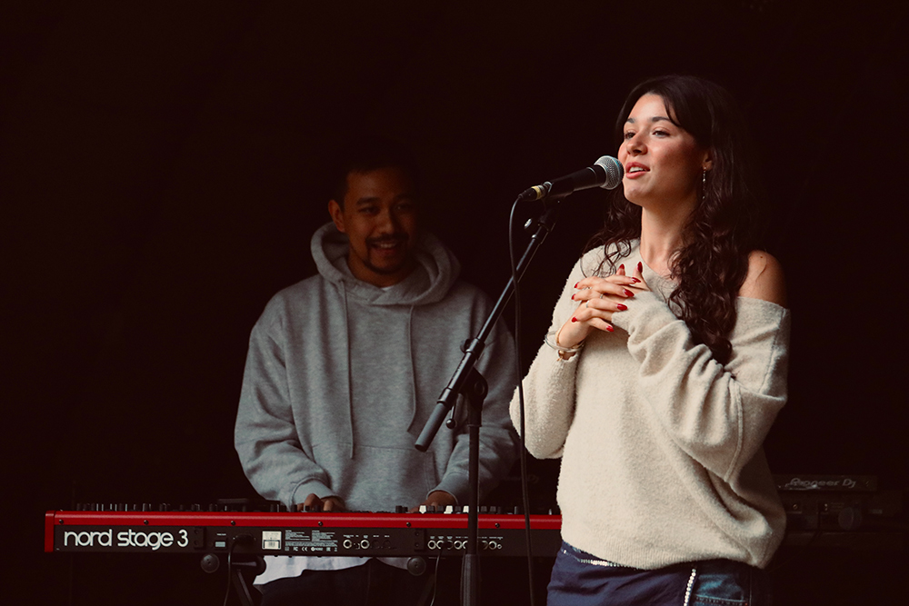 AZURE singer and songwriter performs live on stage with pianist in the background.