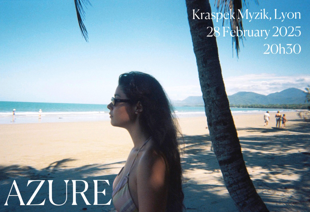 AZURE, Swiss singer and songwriter stands on a beach looking out to the ocean.