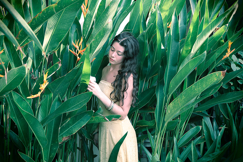 AZURE, Swiss singer and song writer posing in a yellow strapless dress in tropical leaves.