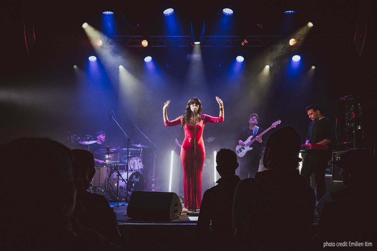 AZURE, Swiss singer/songerwriter performing live with her band at the Premices Festival 2025, Lausanne, wearing a long pink dress.